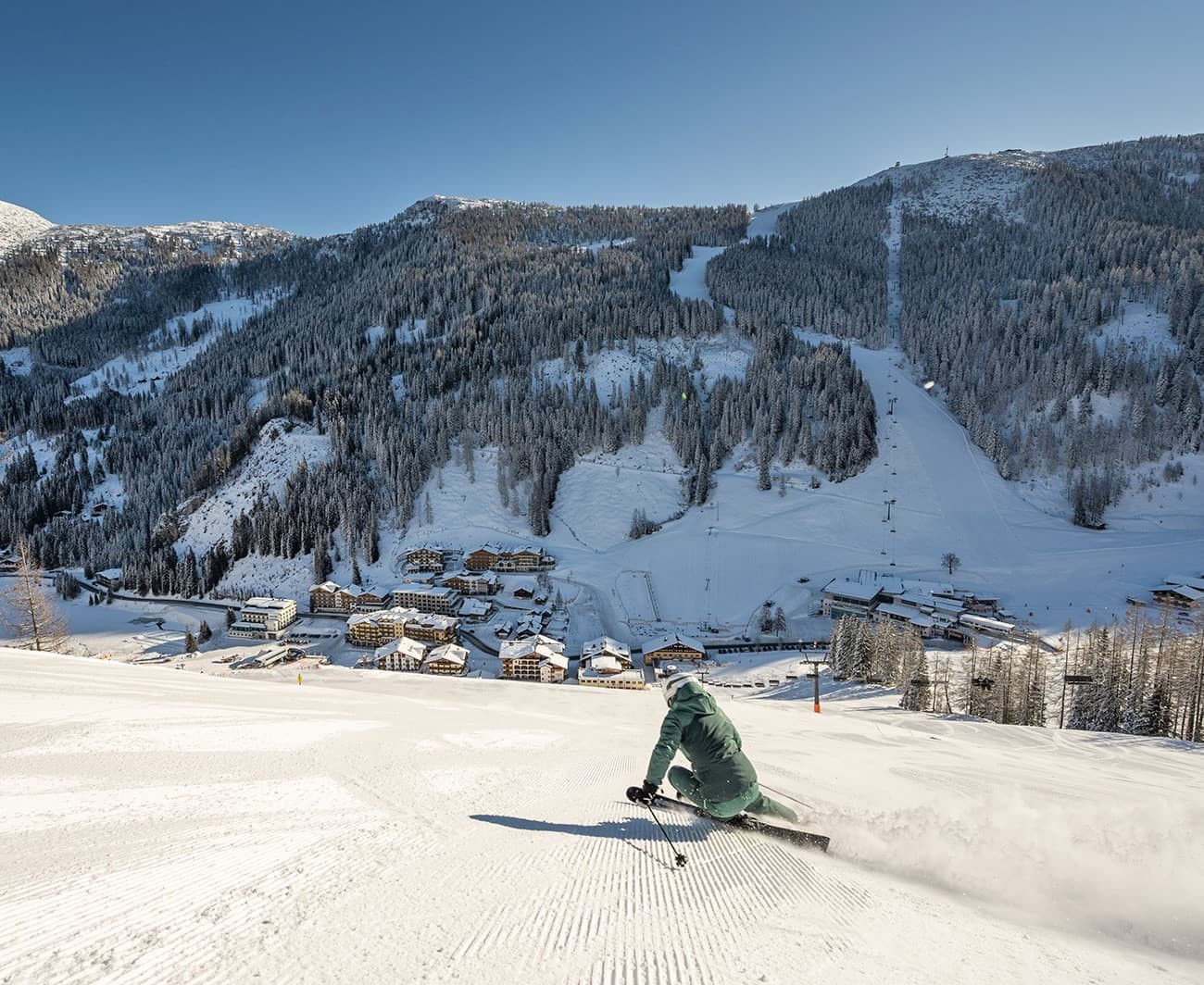 Skifahrer auf verschneiter Piste vor schneebedeckten Bergen und Bäumen